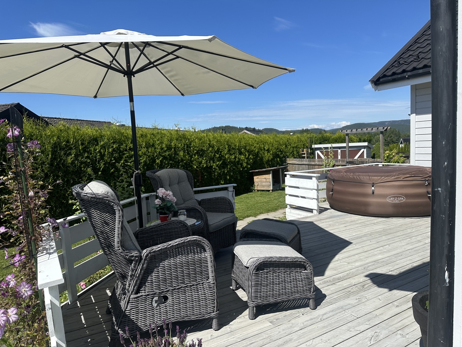 Fin vestvendt uteplass med dør ut fra stuen. Nåværende eier har et boblekar på terrassen. Solen går ned over fjellene i horisonten. 