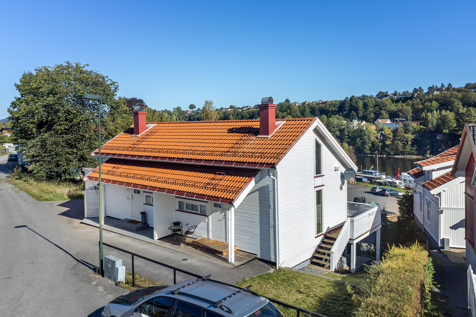 Overbygget inngangsparti med plass til et lite møblement og enkel adkomst til egen terrasse på siden av bygget.