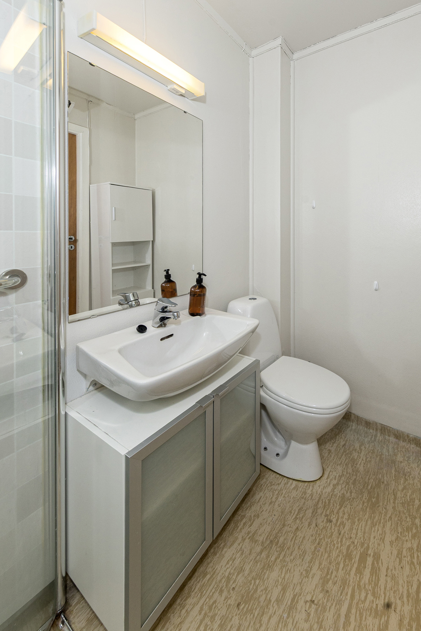 Badet har servant m/underskap og speil, toalett og høyskap