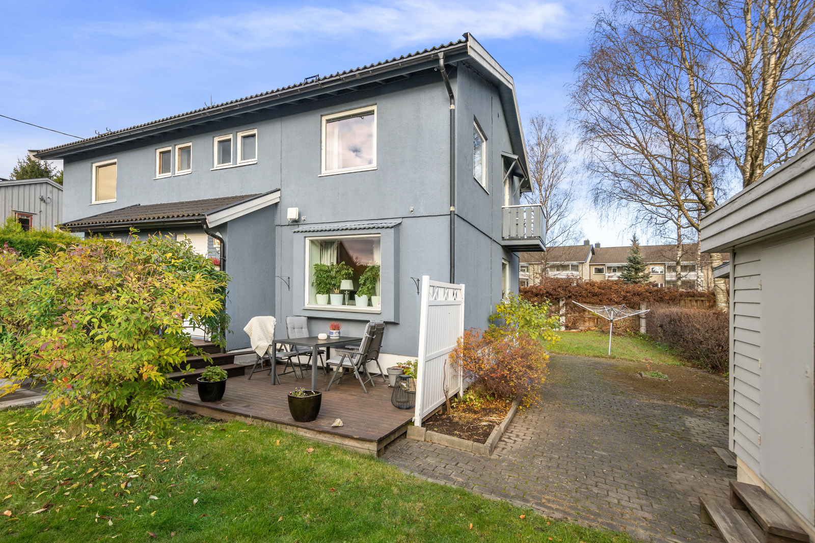 Terrasseområde og pasasje til plen bak huset. Utebod/ sportsbod i tilknyttning til garasje på høyre side i bildet.