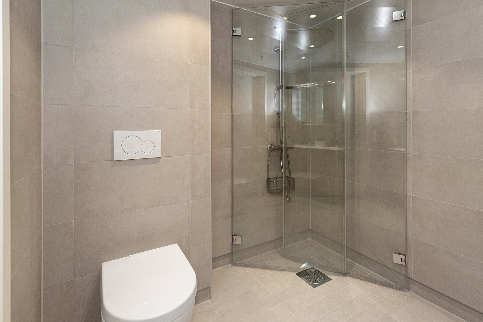 Badet har dusjhjørne, dobbel servant i innredning, vegghengt toalett (Villeroy & Boch) og opplegg for vaskemaskin