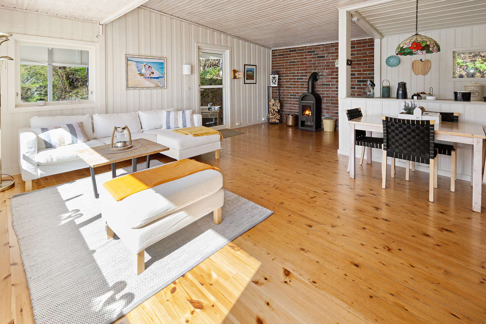 Stor stue med peis, åpen kjøkkenløsning og utgang direkte til overbygget terrasse