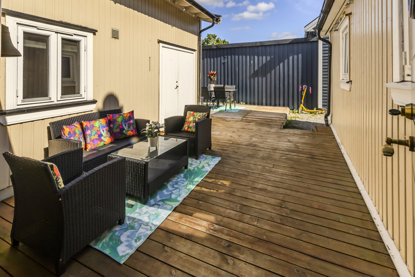 Koselig uteplass med treplatting mellom hovedhus og tilbygg. 