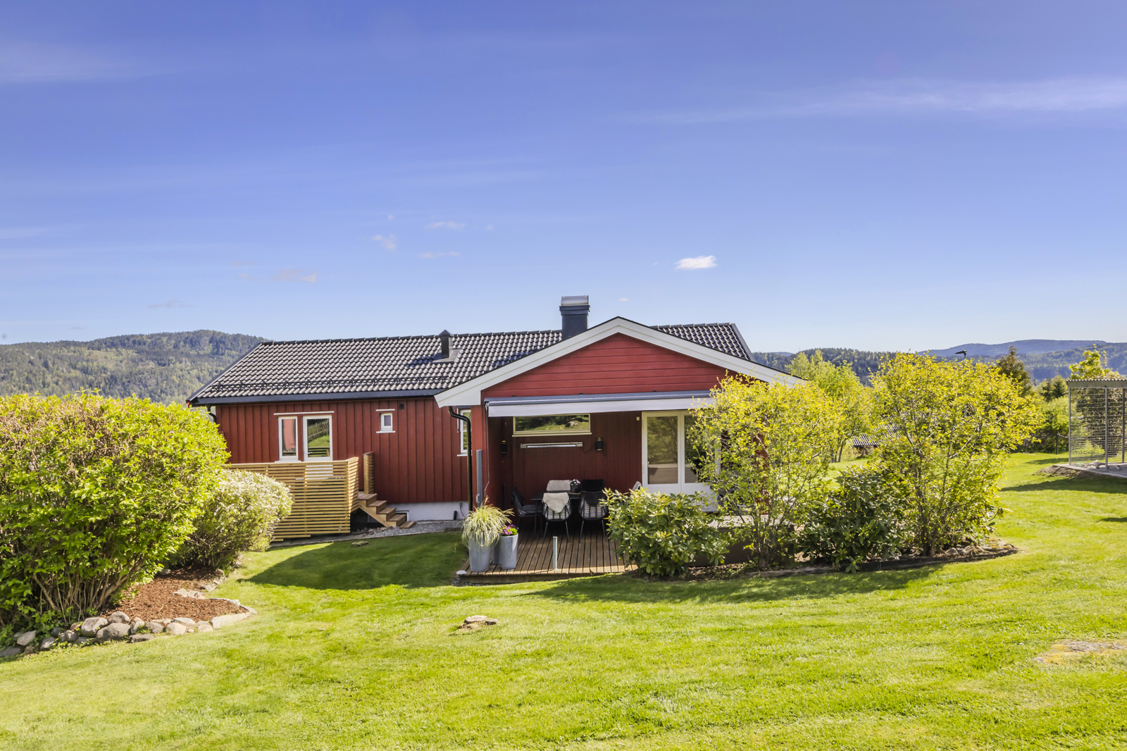 Stemningsbilde med den vestvendte hagen og verandaen. 