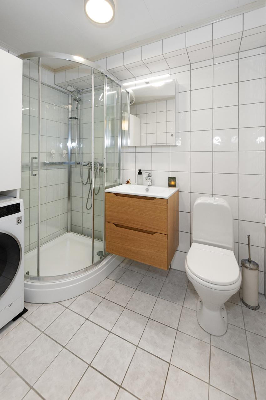 Lyst og trivelig bad med nyere baderomsmøblement. Opplegg til vaskemaskin og tørketrommel.