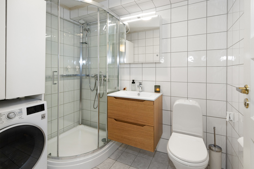 Lyst og trivelig bad med nyere baderomsmøblement. Opplegg til vaskemaskin og tørketrommel.