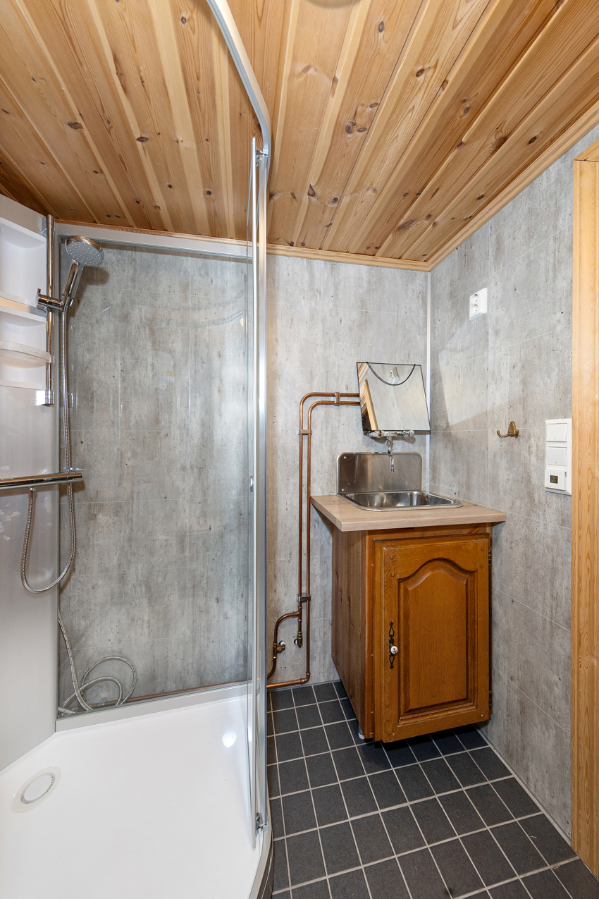 Bad i anneks 1 innholder innredning med benkeplate av laminat og nedfelt utslagsvask. Dusjkabinett og toalett. 