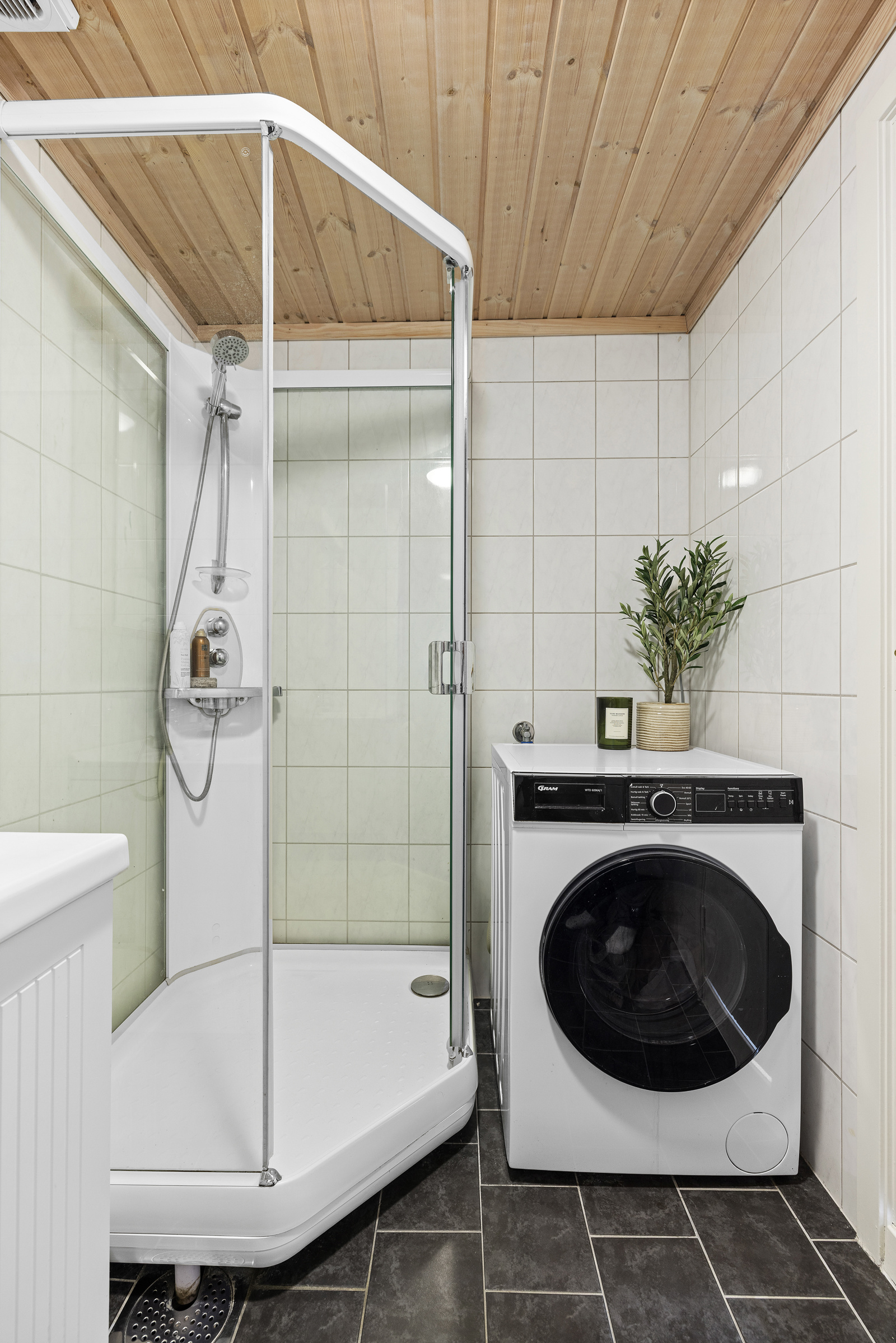 Badet har dusjkabinett, servant i innredning, speil, toalett og opplegg for vaskemaskin/tørketrommel