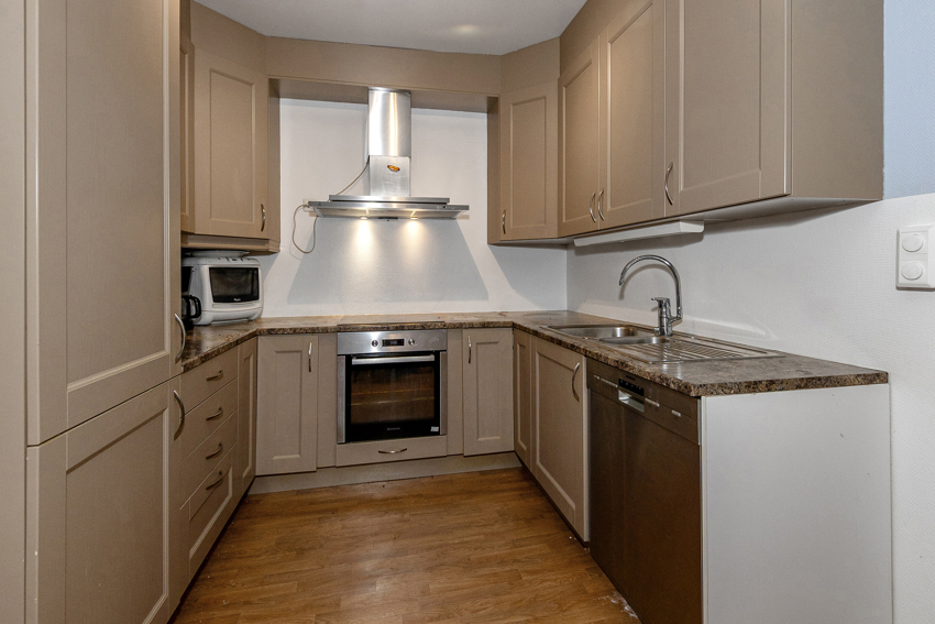 Pent og praktisk kjøkken med integrerte hvitevarer.