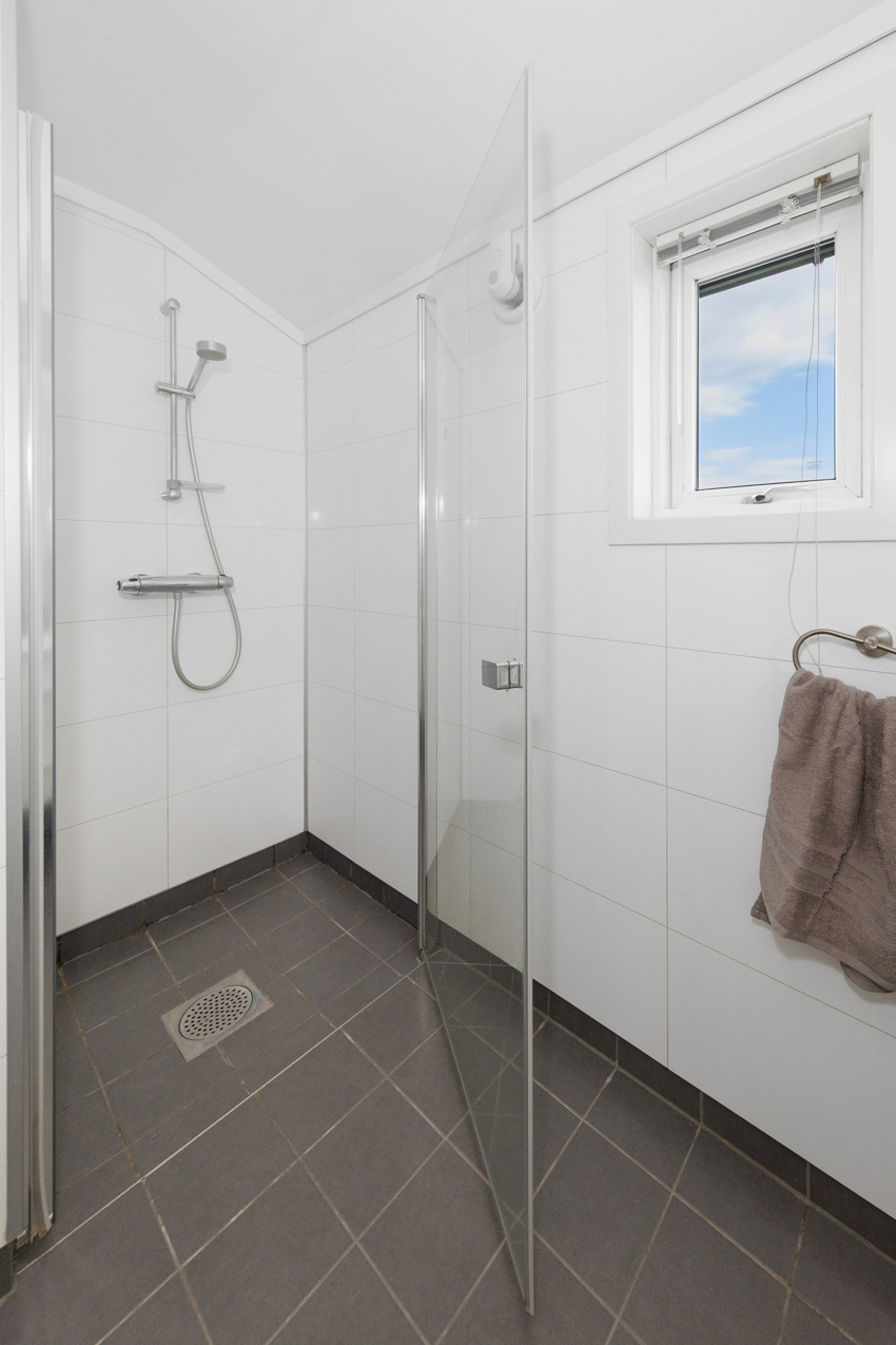 Servant i innredning, speil med lys, vegghengt toalett og dusjnisje med glassdør