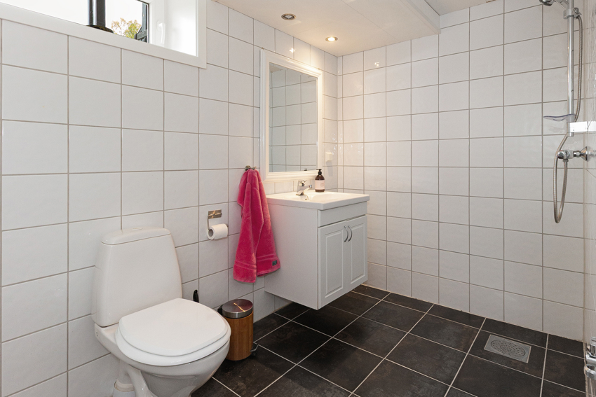 Badet i u.etg. har toalett, åpen dusj, servantskap med nedfelt servant og opplegg for vaskemaskin.