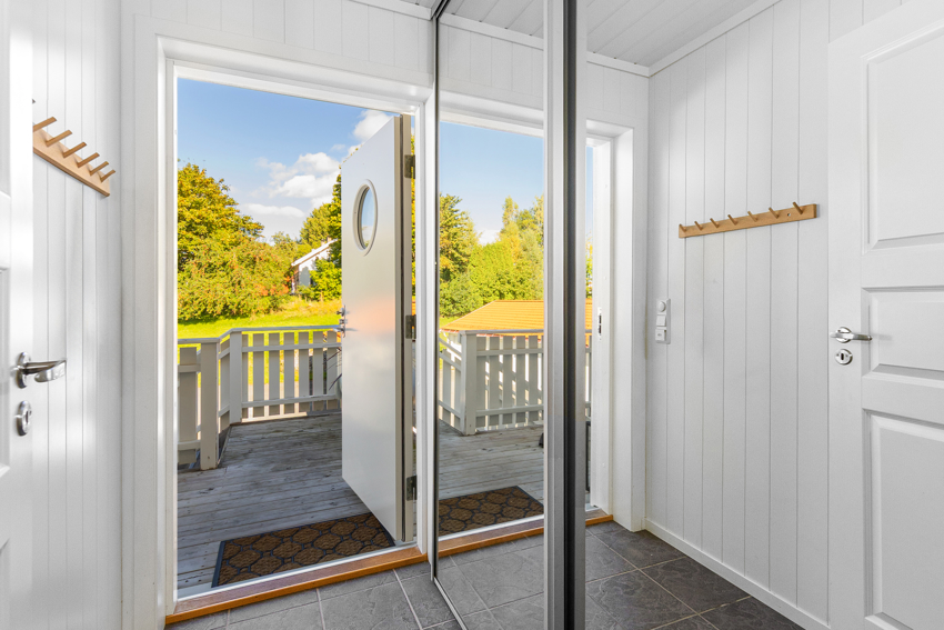Flislagt gang med varmekabler og praktisk skyvedørsgarderobe med speil - gir inntrykk av romlig gang og god plass til oppbevaring av sko og jakker.