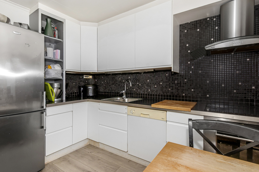 Lyst og pent kjøkken med takhøye skap.