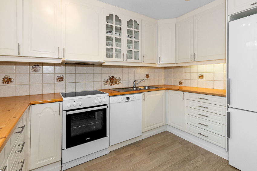 Hvit profilert kjøkkeninnredning med fliser over benk