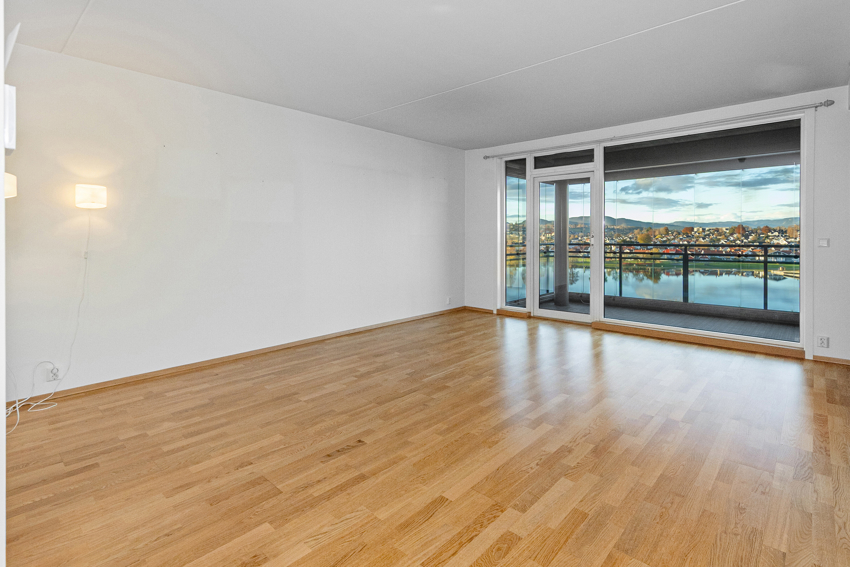 Stuen med pene, lyse, malte flater og klassisk parkett på gulv. 