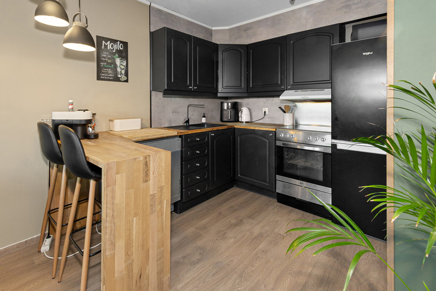 Kjøkkenet har malt innredning og plater over benk - Barløsning mot stuedelen