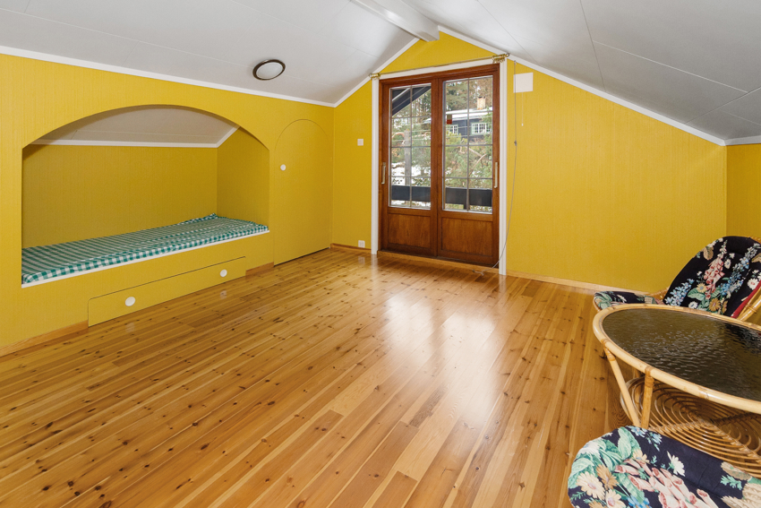 Romslig soverom i 2. etasjen med dør ut til overbygget balkong mot vest.