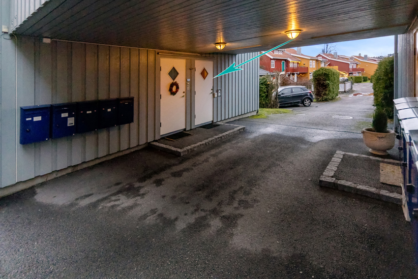 Inngangen til leiligheten er markert med pil. Her er det calling system så man låser opp fra leiligheten. Praktisk med overbygg hvis du skal hentes med bil. Garasjen er rett over vegen.