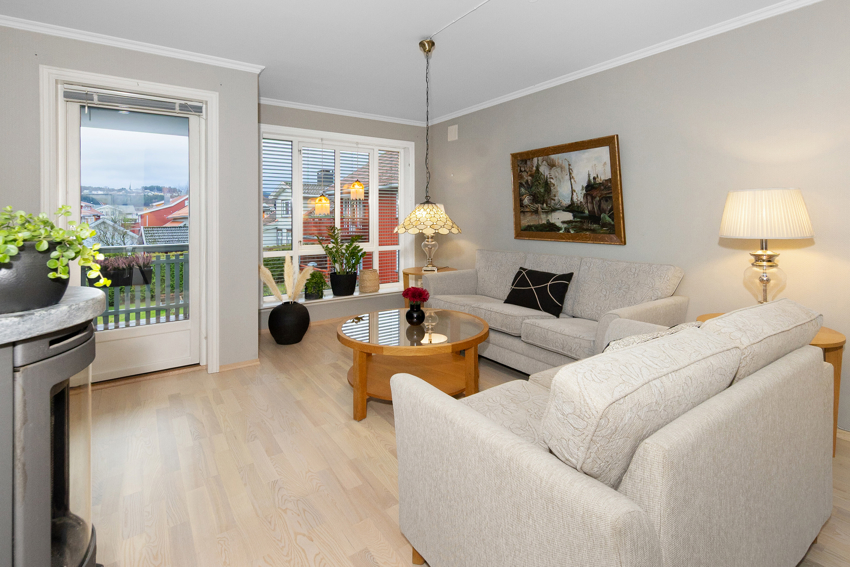 Romslig stue med vinduer ut mot sameiets fellesareal. Dør ut til terrassen til venstre. Vedovn i kleberstein som gir god og lun varme. 