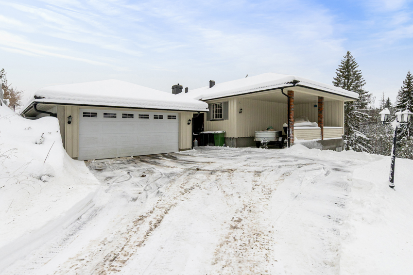 Eneboligen har dobbelgarasje og carport. Asfaltert gårdsplass. 