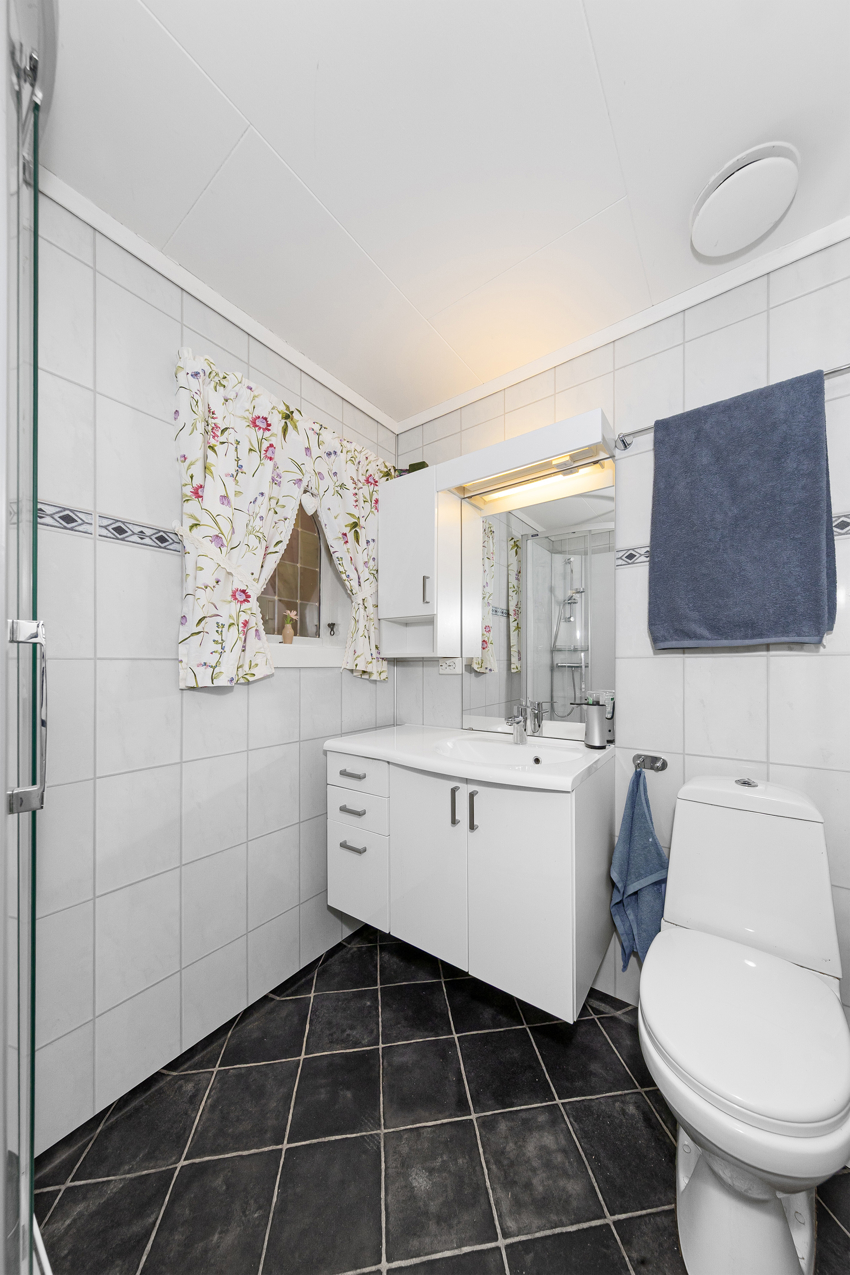 Badet har dusjkabinett, servantinnredning og wc.