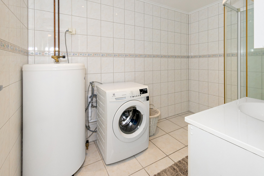 Baderom innehar Vask med underskap, sideskap, speil og dusjkabinett.