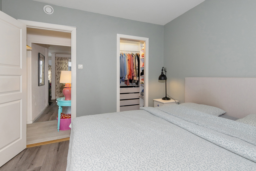 Tilliggende walk-in garderobe med pratisk innredning: skohyller, dobbelt og enkelt heng, skuffer og hyller.