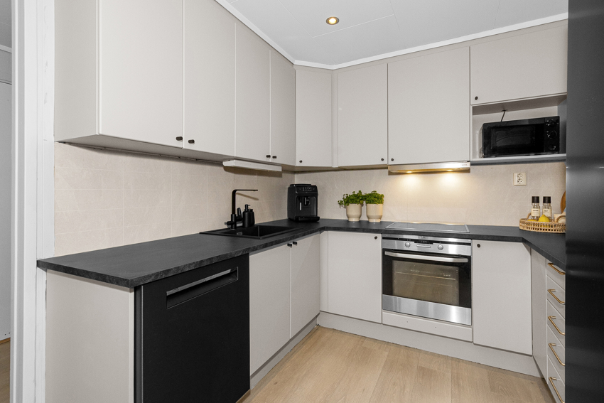 Malt kjøkkeninnredning med flatte fronter. Plater over benk