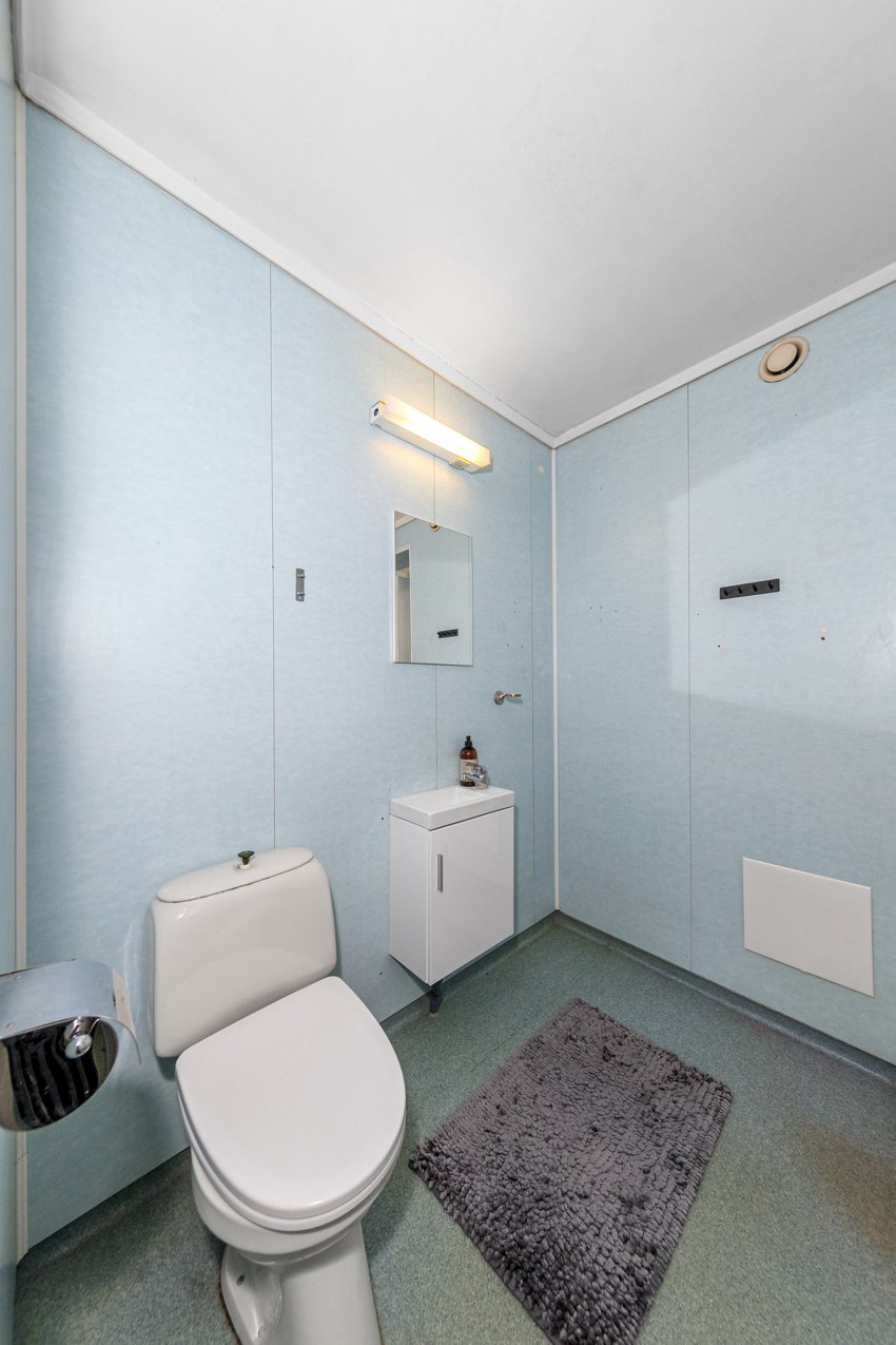 Bad med dusjkabinett, gulvstående toalett og opplegg til vaskamaskin.