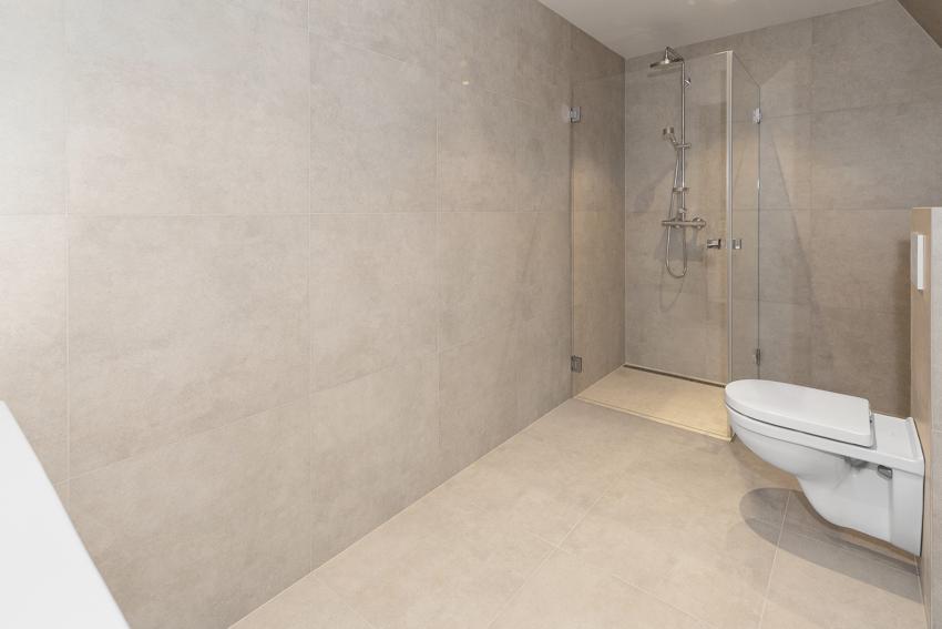 Stort bad med dusjnisje, vegghengt toalett og servant med møbel. 