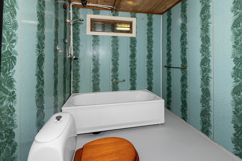 Bad i kjeller med badekar/dusj på vegg, wc og servant. 