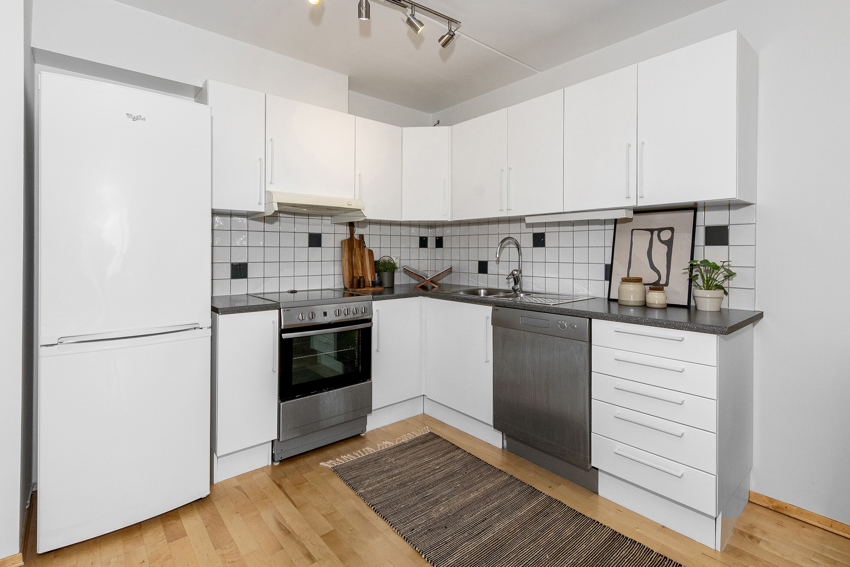 Kjøkkenet fra byggeår er pent og funksjonelt, med slette fronter, laminert benkeplate og fliser over benk.